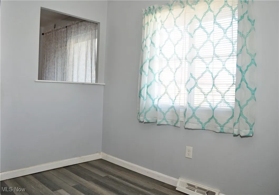 Empty room with baseboards and dark wood-style floors