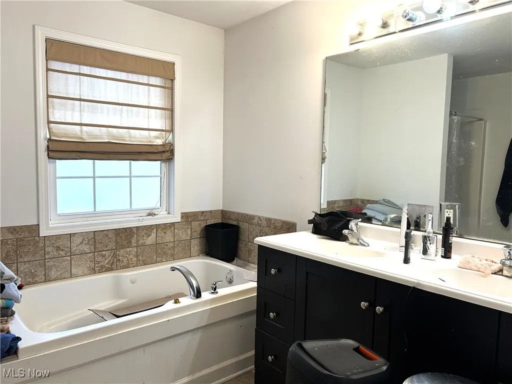 Owner's bathroom with double sink vanity, a bath, and a shower