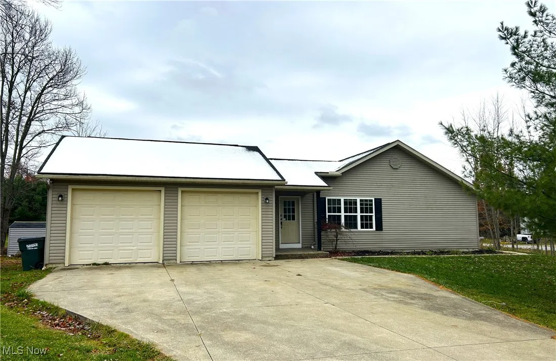Ranch-style house with wide driveway, a front yard, and an attached garage