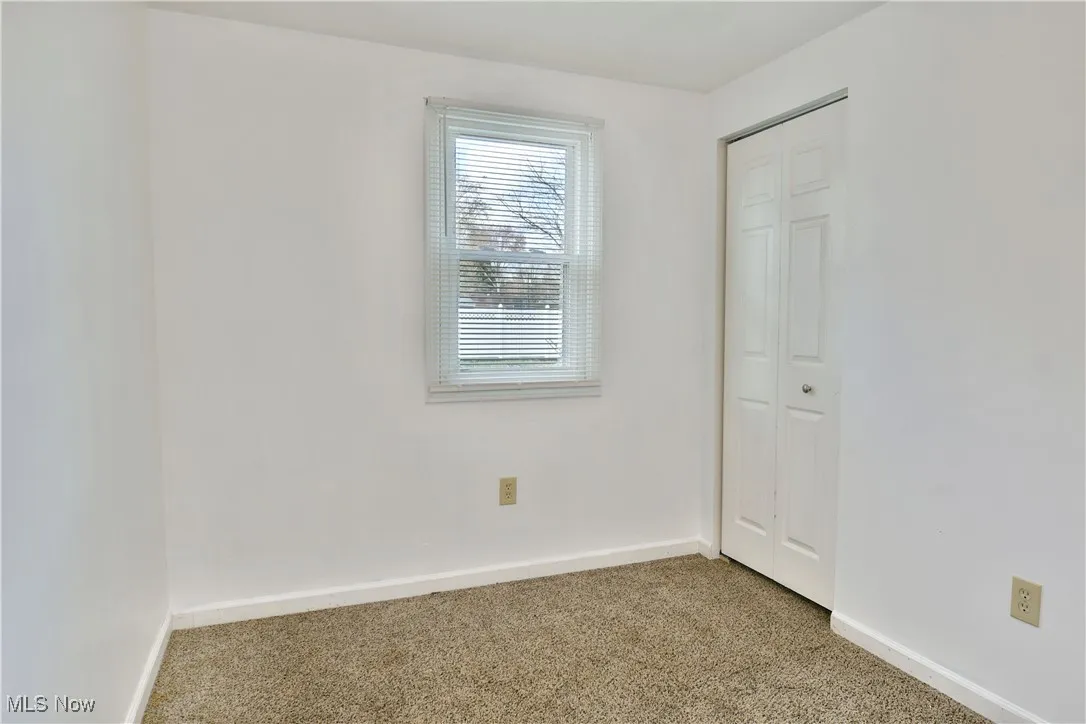 Carpeted spare room featuring baseboards