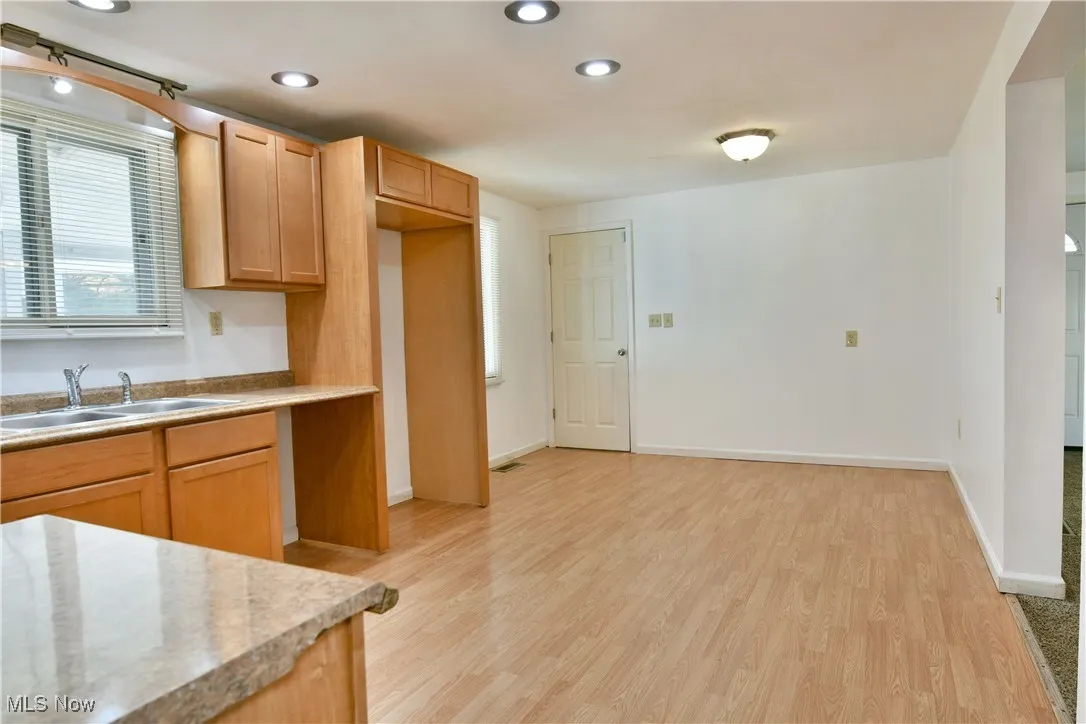 Kitchen featuring light wood-type flooring, recessed lighting, plenty of natural light, light brown cabinetry, and light stone countertops