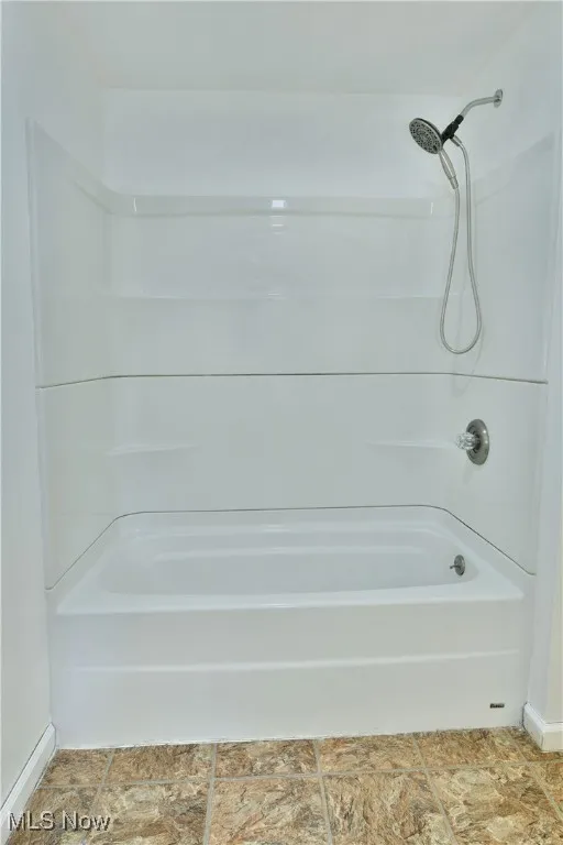 Bathroom with baseboards and tub / shower combination