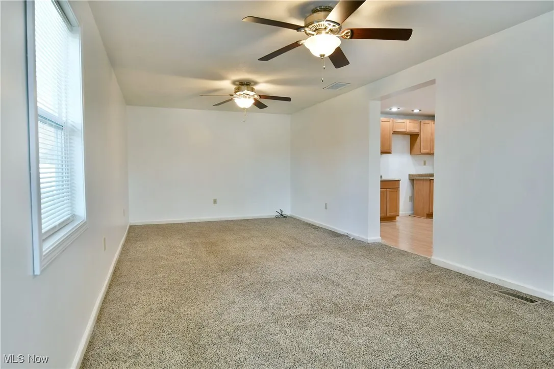 Spare room featuring light colored carpet and ceiling fan