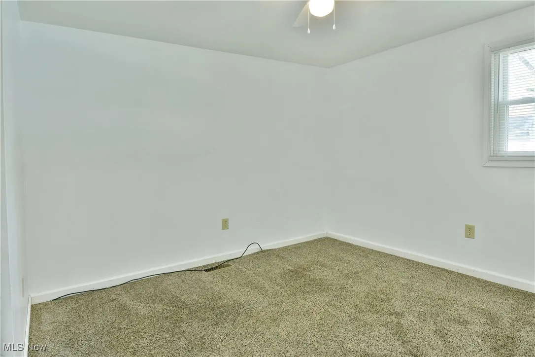 Carpeted empty room with baseboards and a ceiling fan