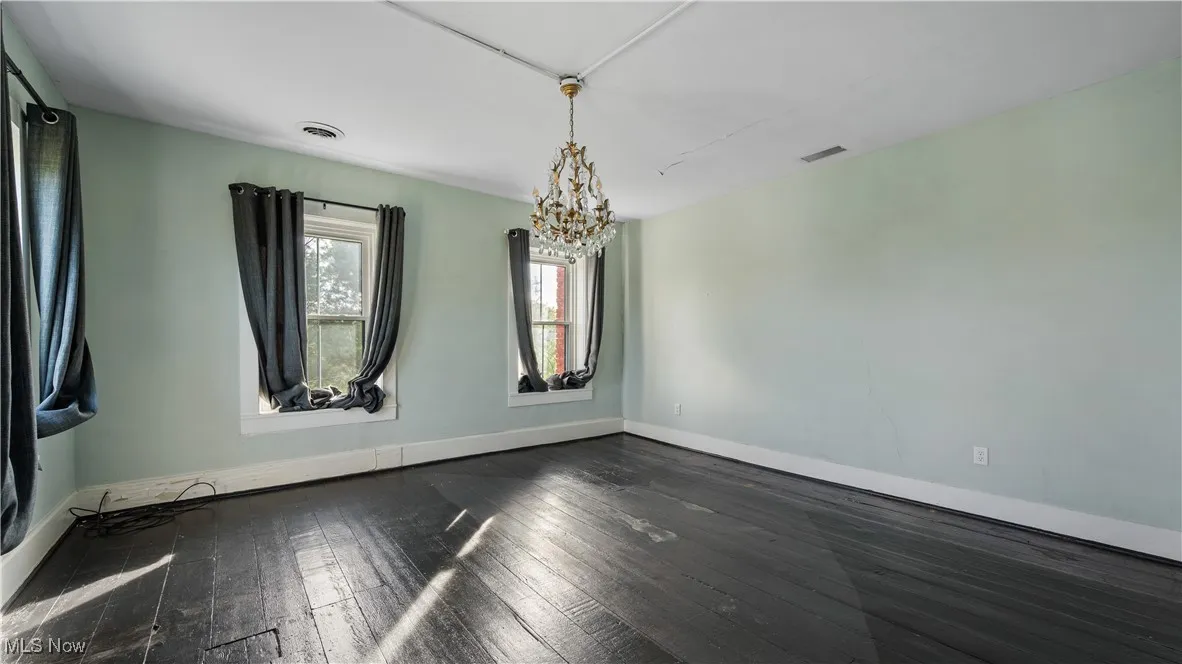 Bedroom with dark wood finished floors and a chandelier