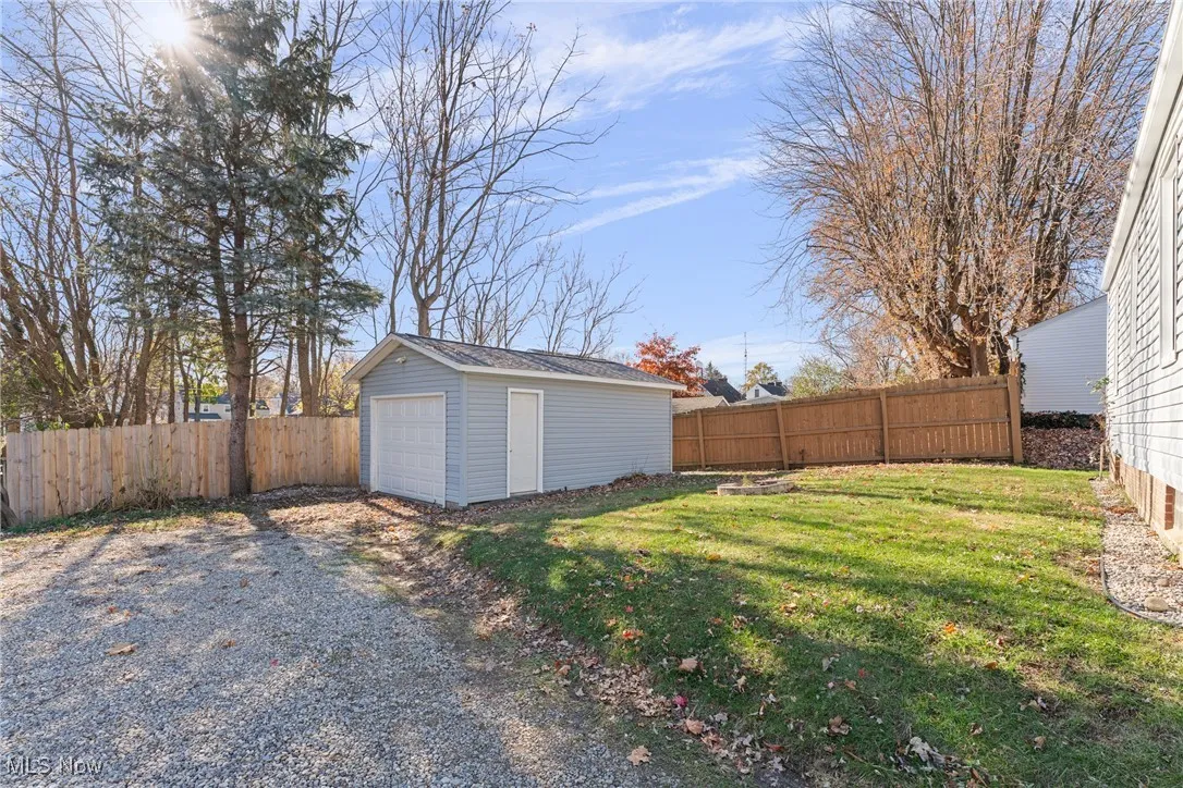 Fenced backyard with an outbuilding, a detached garage, and driveway