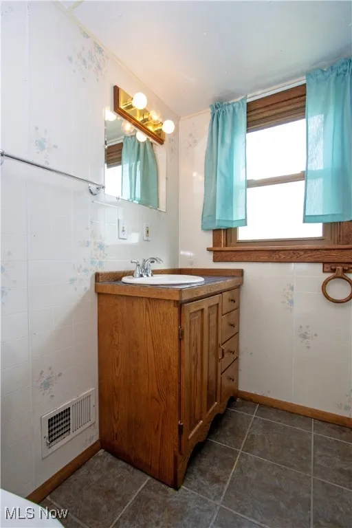 Half bath featuring vanity and dark tile patterned floors