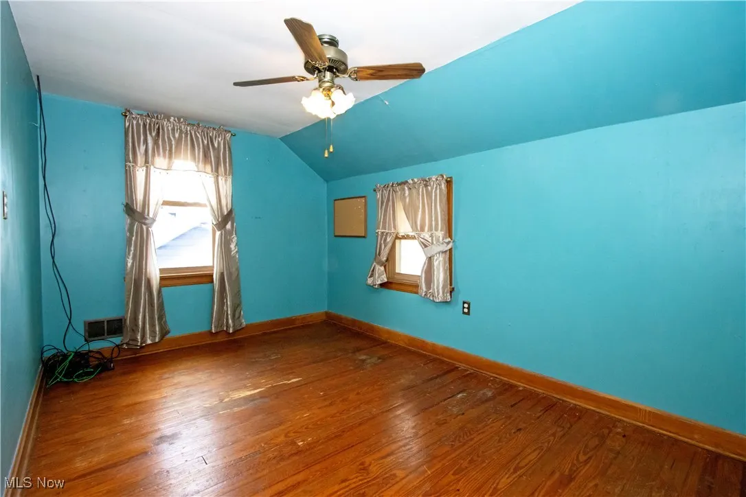 Empty room with wood-type flooring, lofted ceiling, and ceiling fan