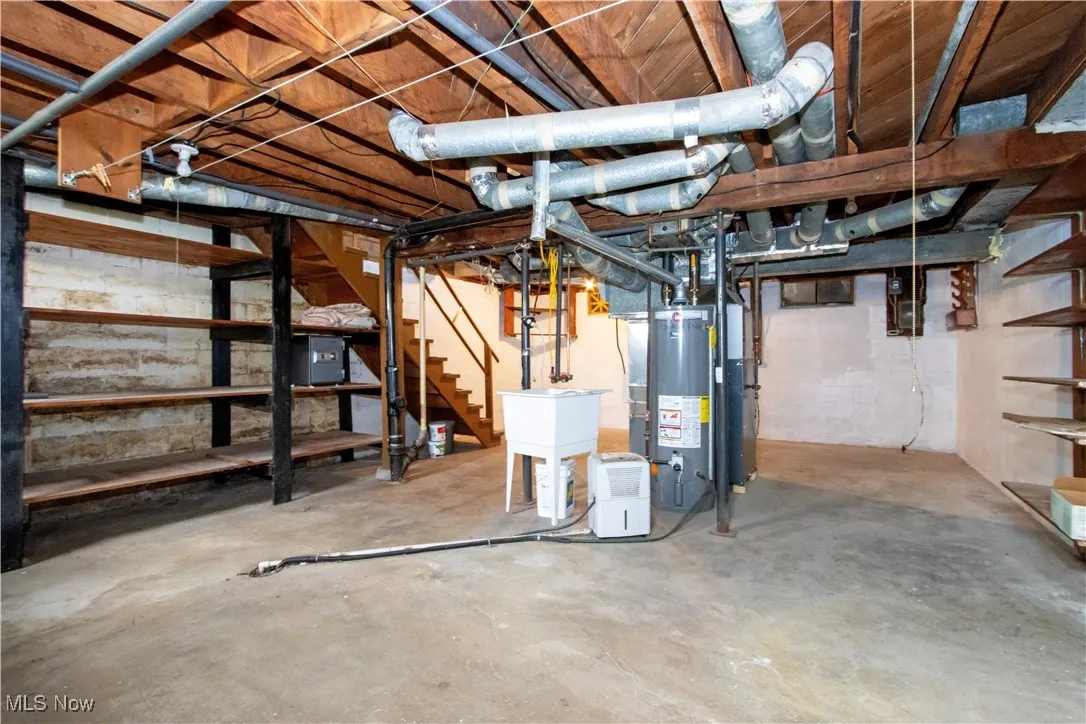 Unfinished basement with stairway and water heater