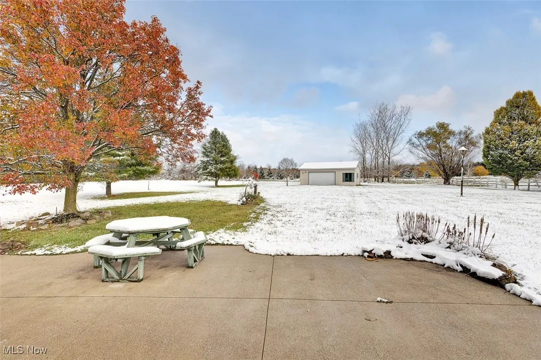 Yard layered in snow featuring an outbuilding and a patio