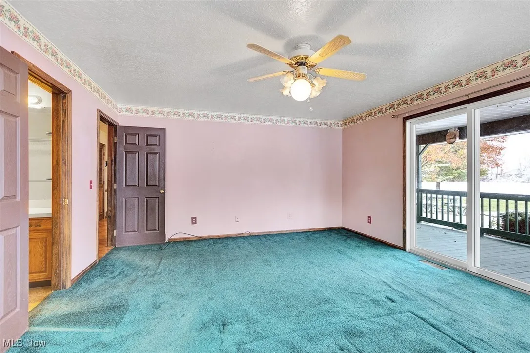 Carpeted empty room with a textured ceiling and a ceiling fan