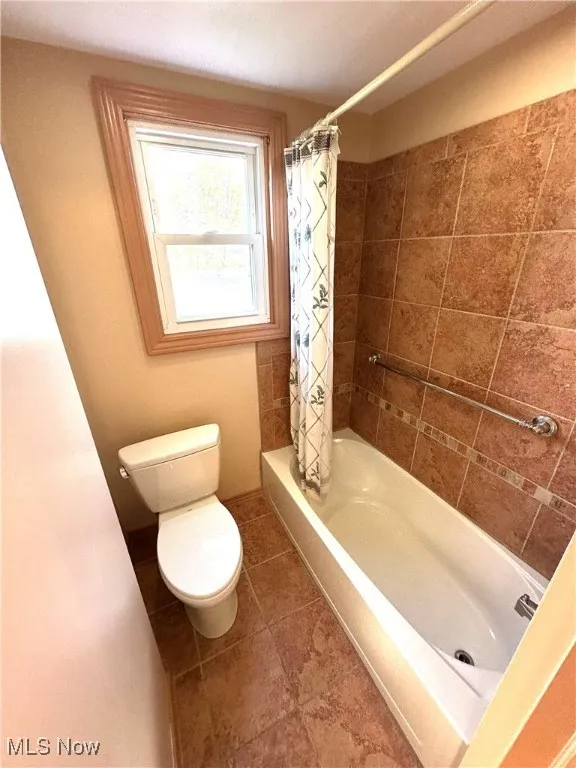 Full bath featuring shower / tub combo and tile patterned flooring