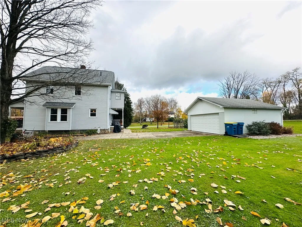 View of grassy yard with an outdoor structure, a patio area, and a detached garage