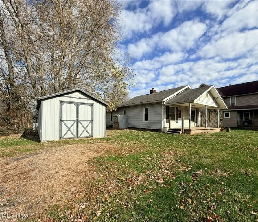 Rear view of house featuring a storage shed, a yard, and a chimney