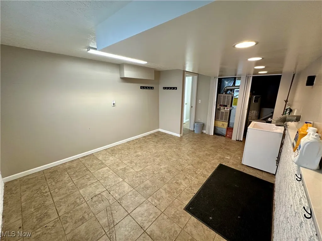 Finished below grade area with recessed lighting, electric water heater, a textured ceiling, and washer / dryer