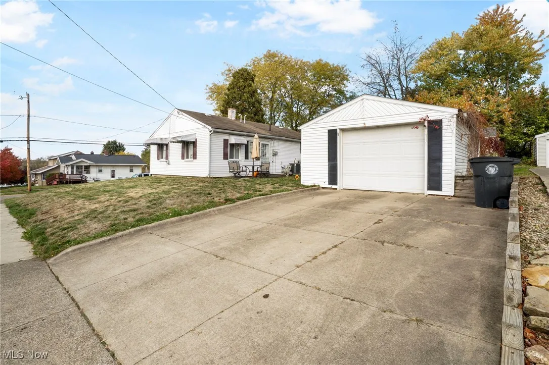 Ranch-style house featuring a front lawn, concrete driveway, an outdoor structure, and a detached garage