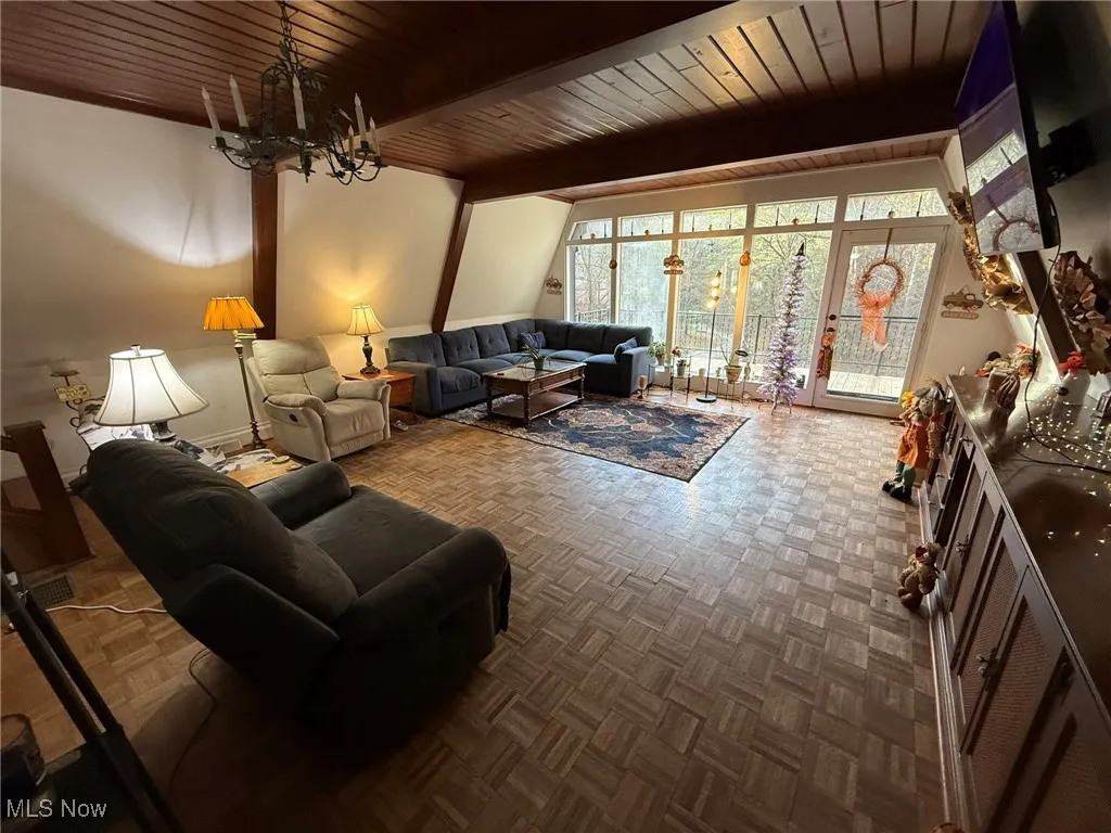Living room with a chandelier and a wood ceiling with exposed beams