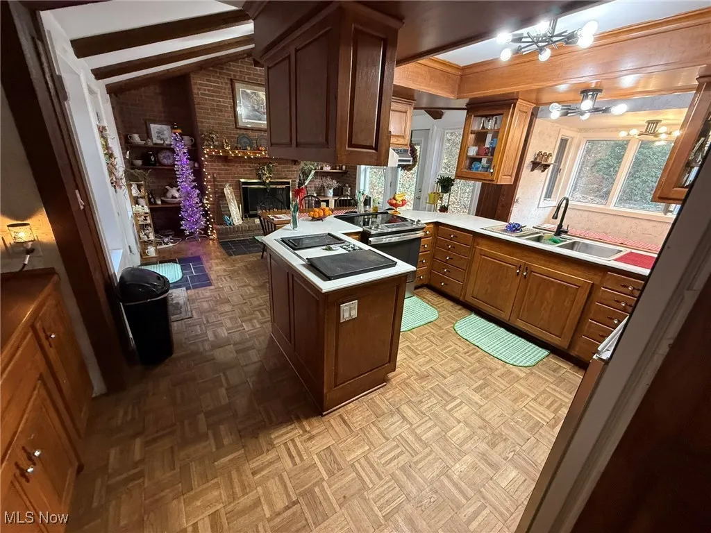 Kitchen featuring light countertops, a peninsula, range with electric stovetop, and a fireplace