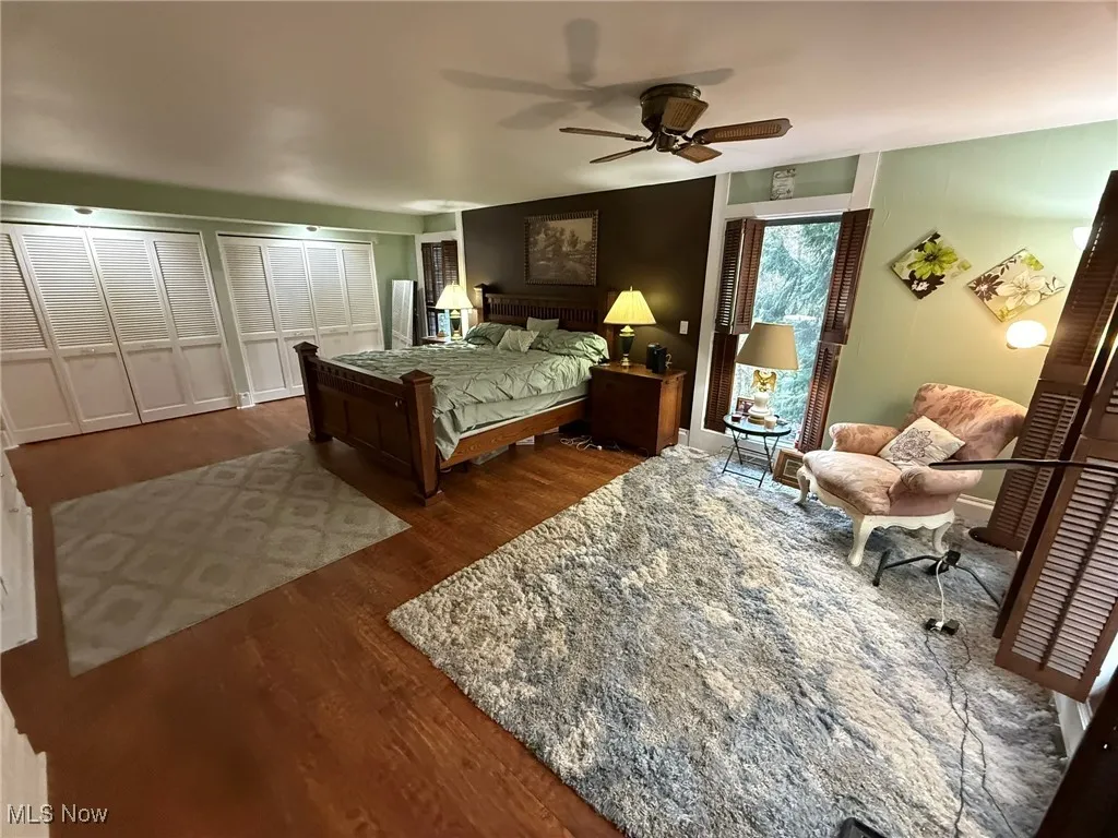 Bedroom with two closets, dark wood-type flooring, and ceiling fan