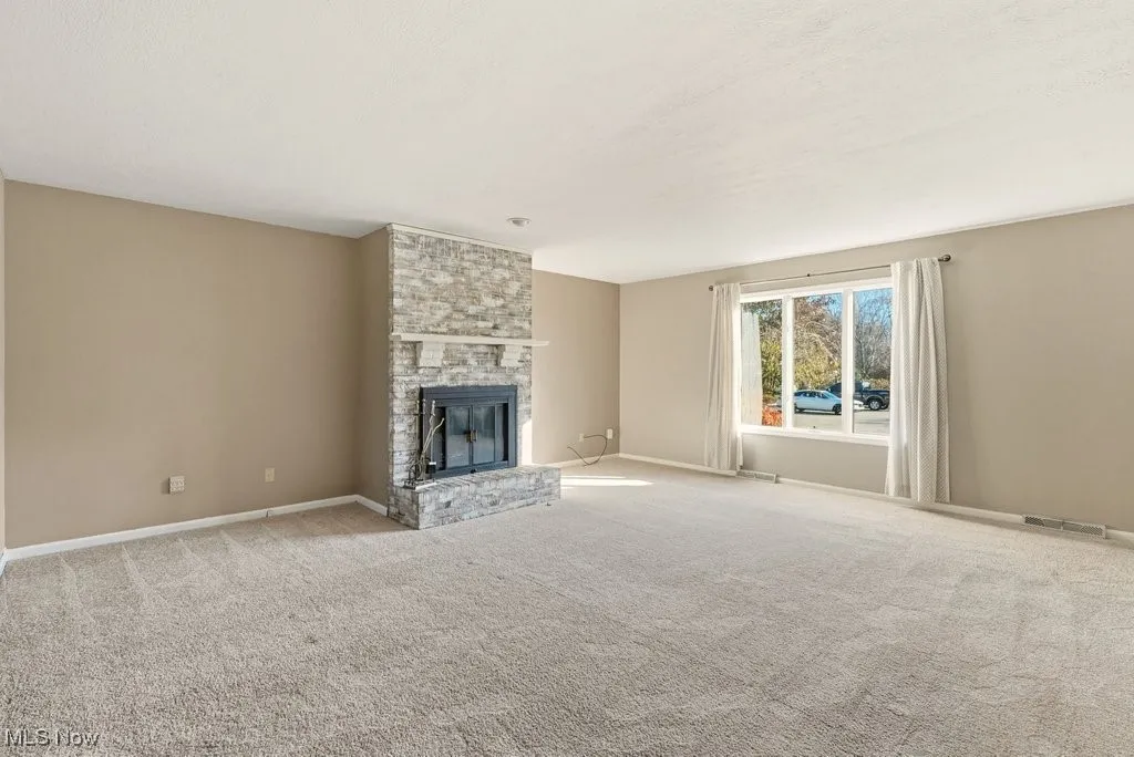 Unfurnished living room featuring a fireplace and carpet flooring