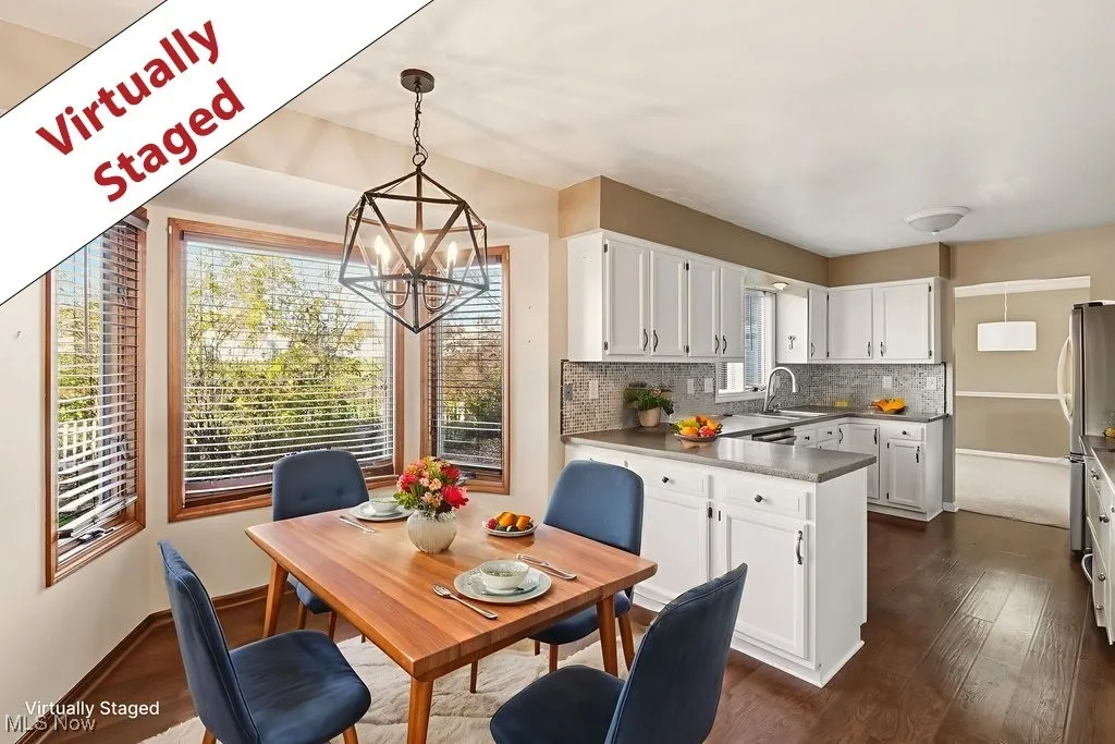 Kitchen featuring pendant lighting, a peninsula, white cabinetry, a chandelier, and decorative backsplash