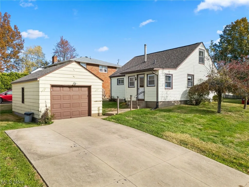 View of front of house featuring an outdoor structure, a front yard, concrete driveway, and a garage