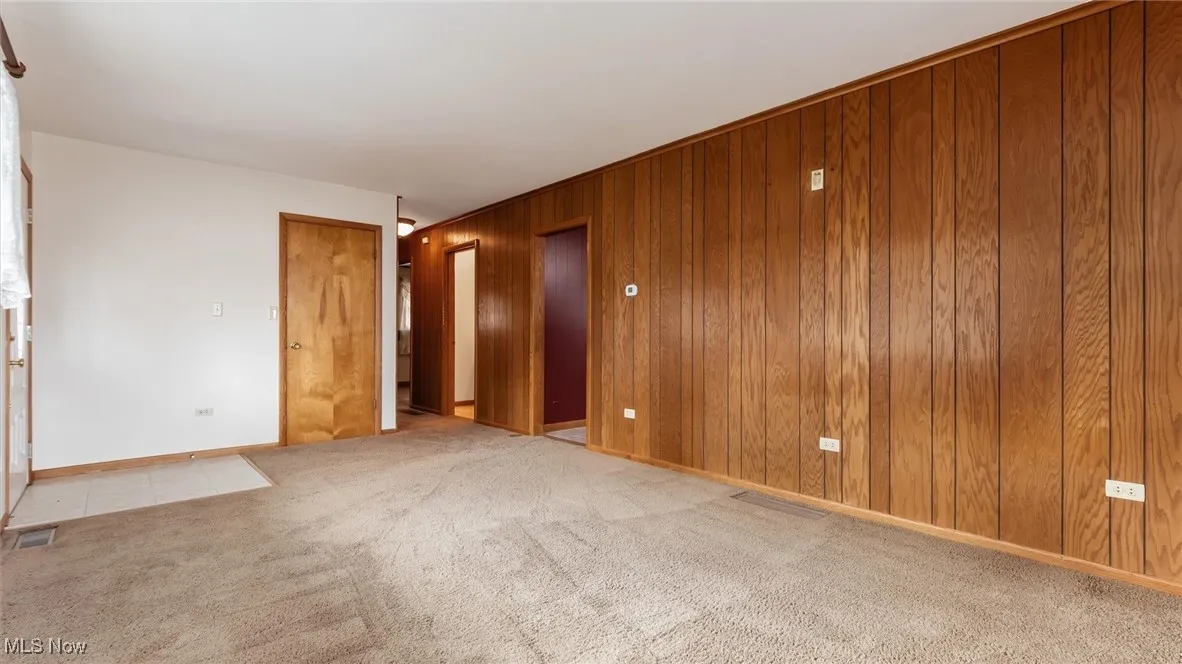 Unfurnished room with light carpet and wooden walls