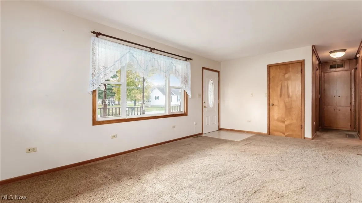 Unfurnished room with light colored carpet and baseboards
