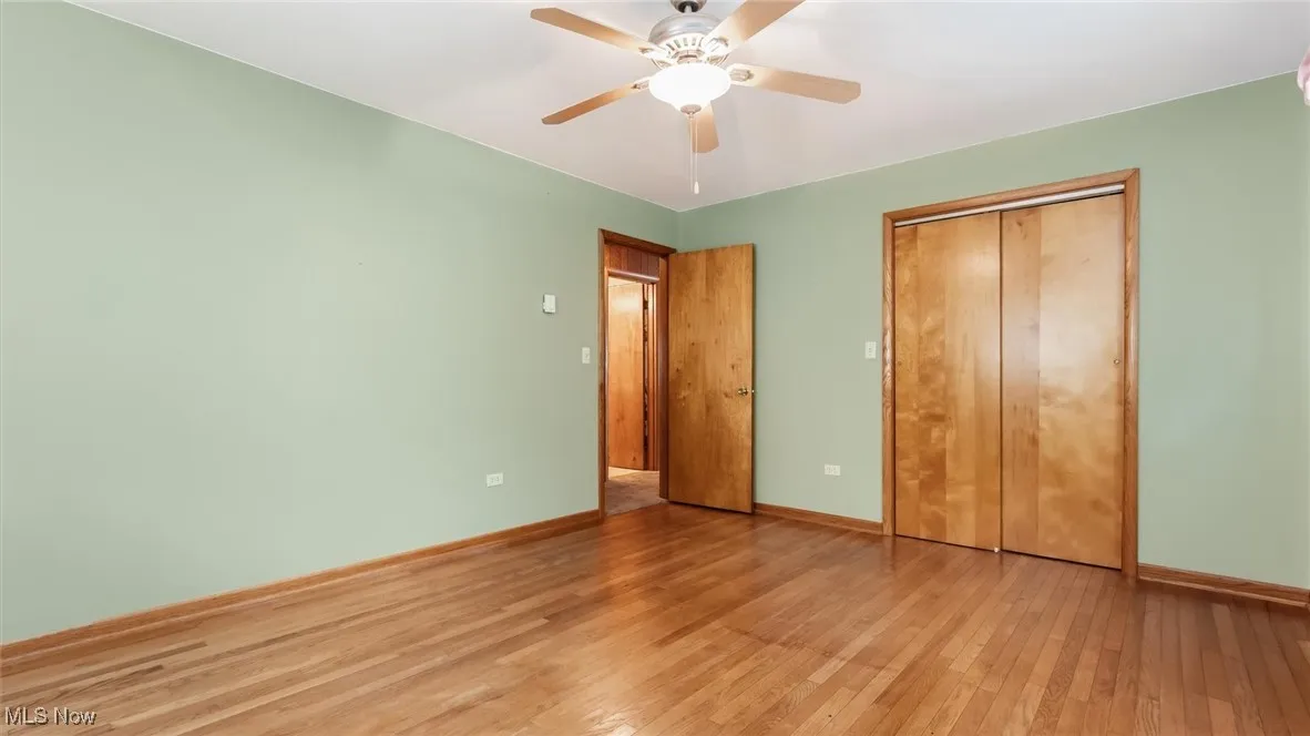 Unfurnished bedroom with wood-type flooring, a ceiling fan, and a closet