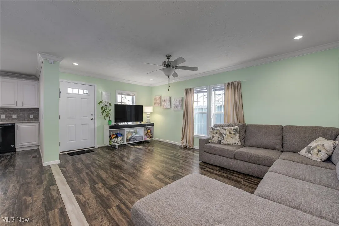 Living area featuring crown molding, recessed lighting, dark wood finished floors, and ceiling fan
