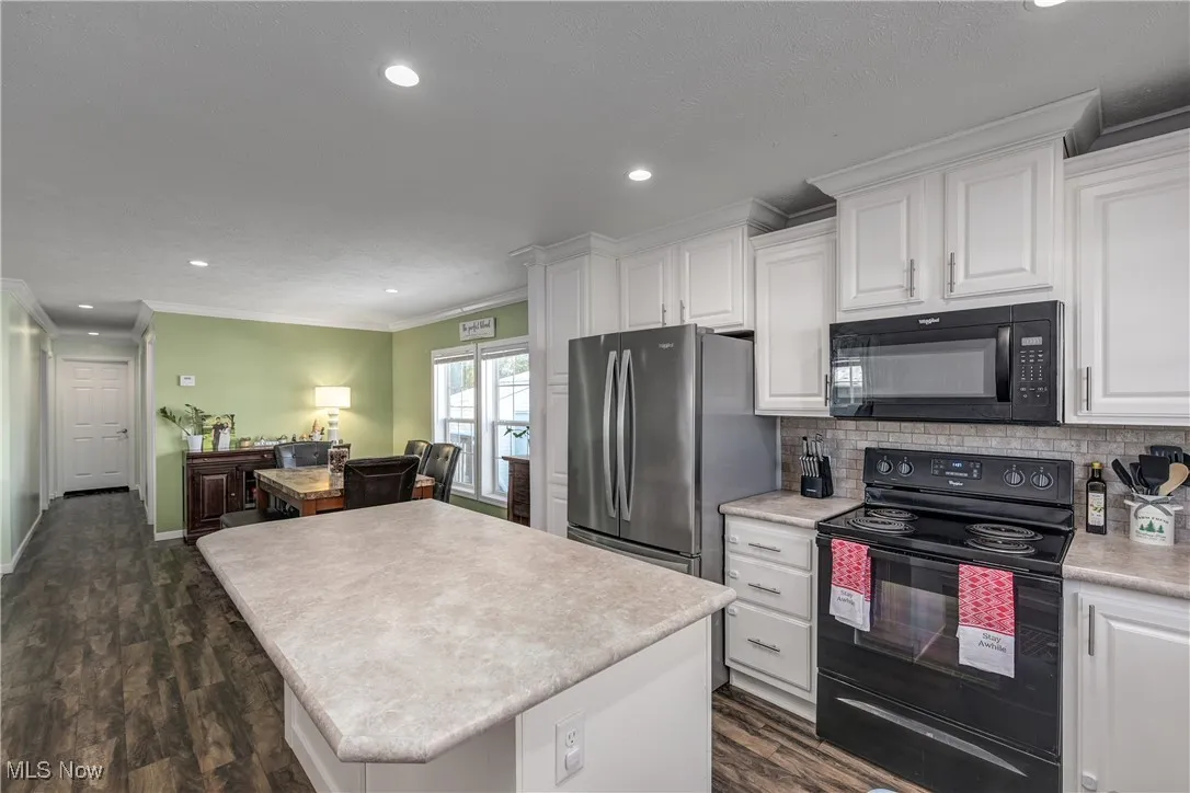 Kitchen with black appliances, ornamental molding, recessed lighting, white cabinetry, and tasteful backsplash