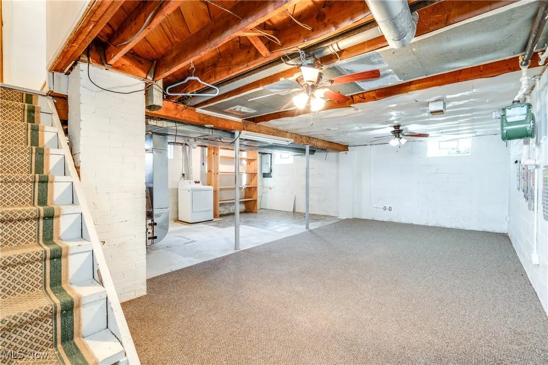 Below grade area with washer / dryer, stairs, a ceiling fan, and heating unit