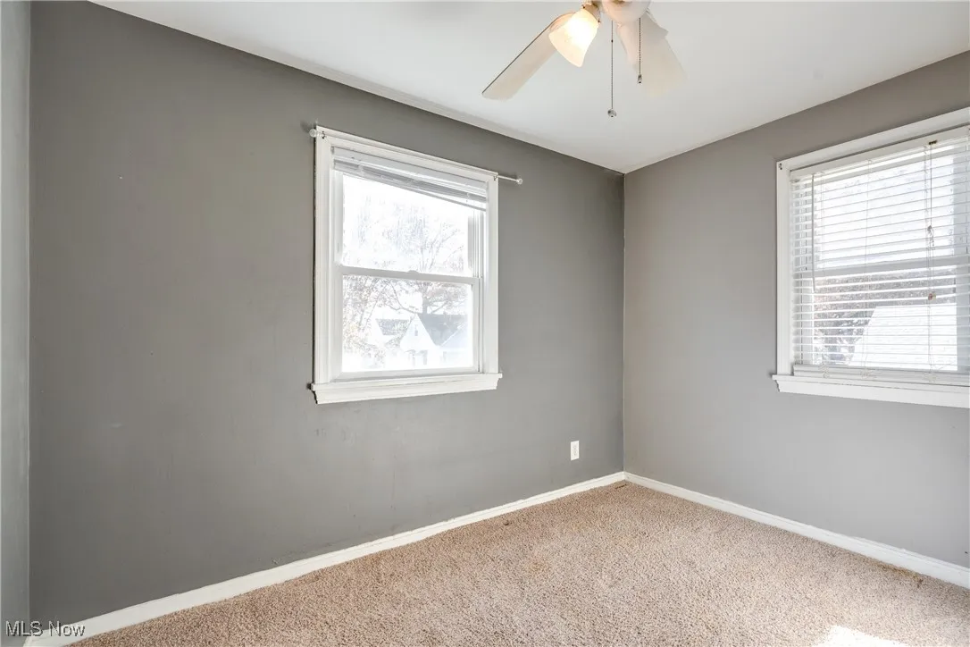 Carpeted empty room with plenty of natural light and a ceiling fan