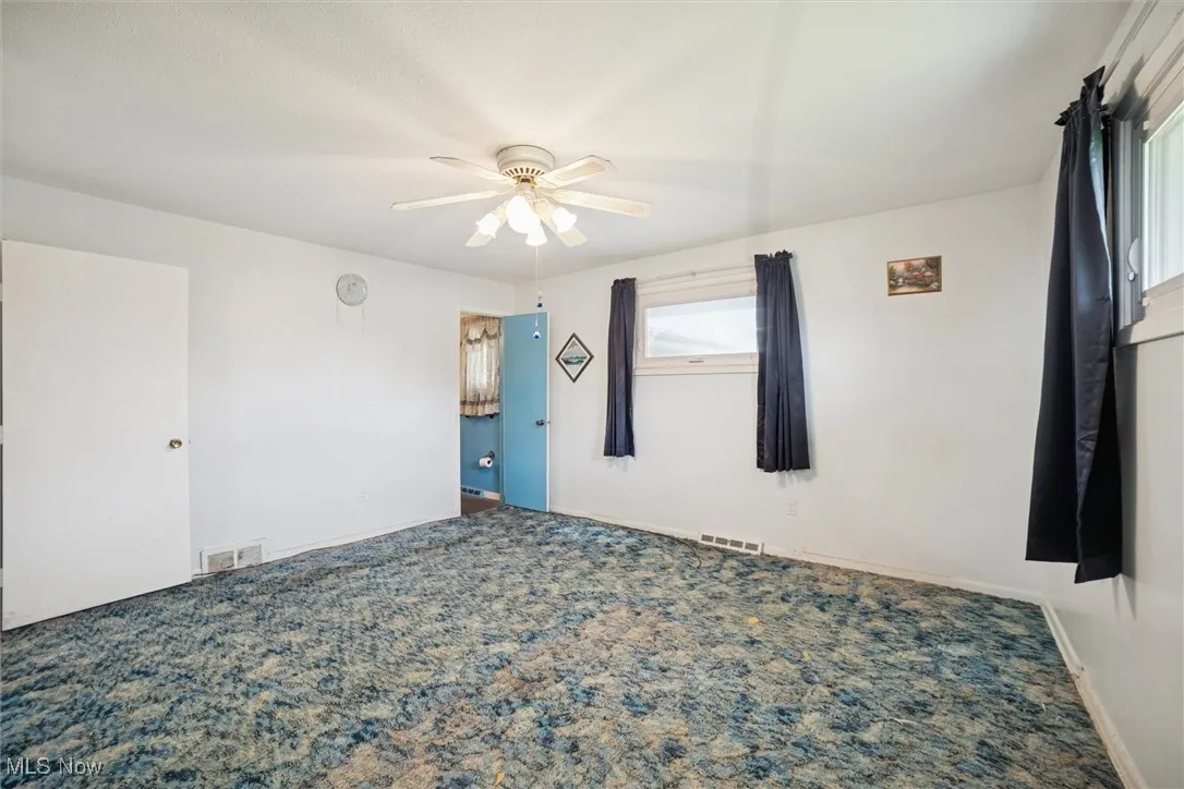 Carpeted spare room with baseboards and ceiling fan