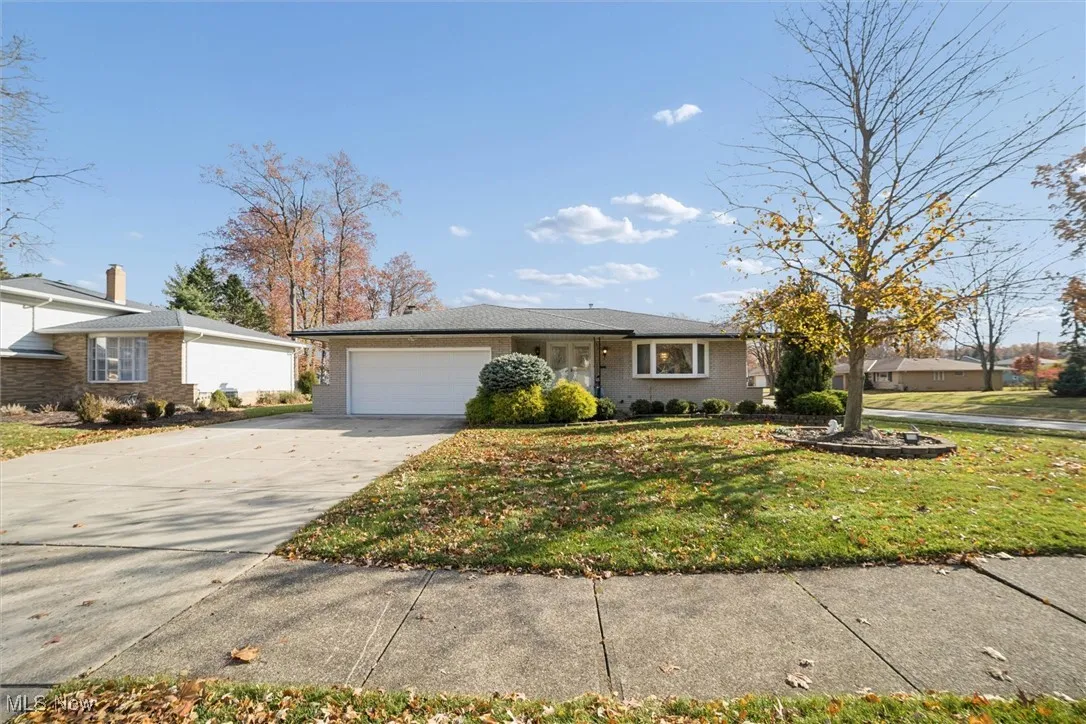 Ranch-style home with concrete driveway, a front yard, and a garage