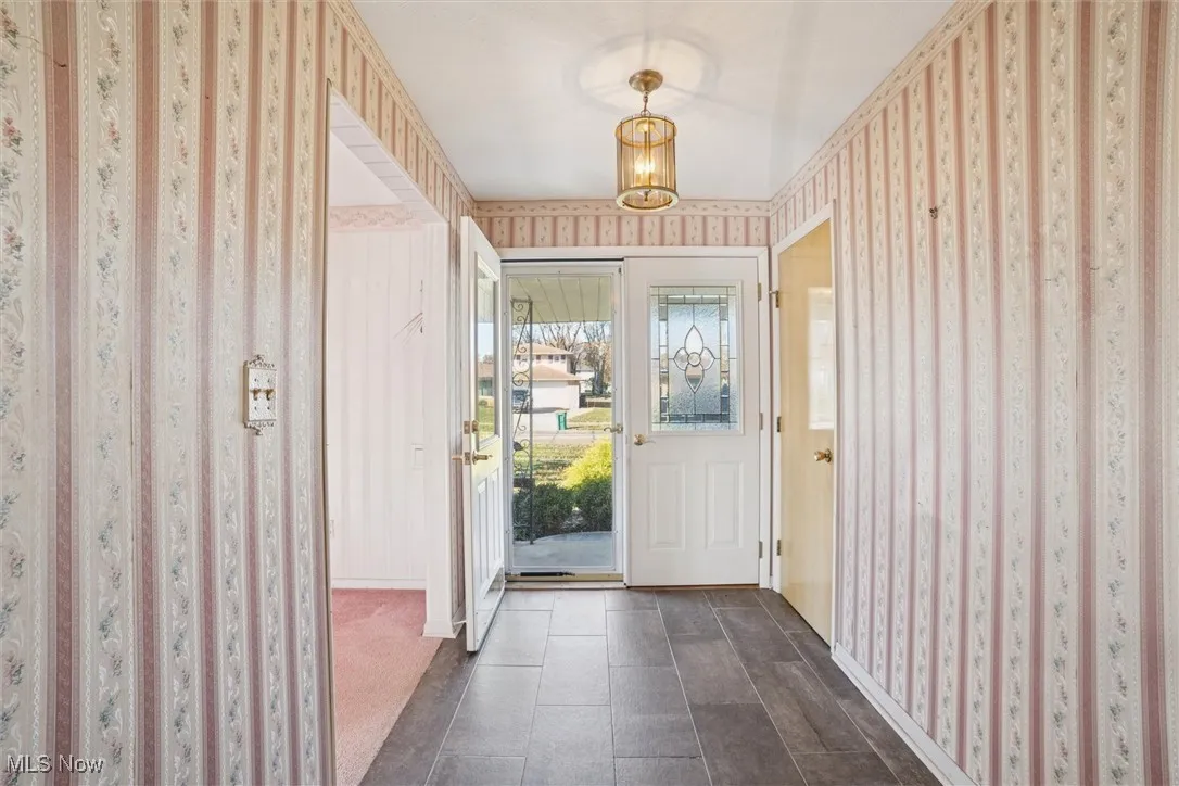Entryway featuring wallpapered walls and a chandelier