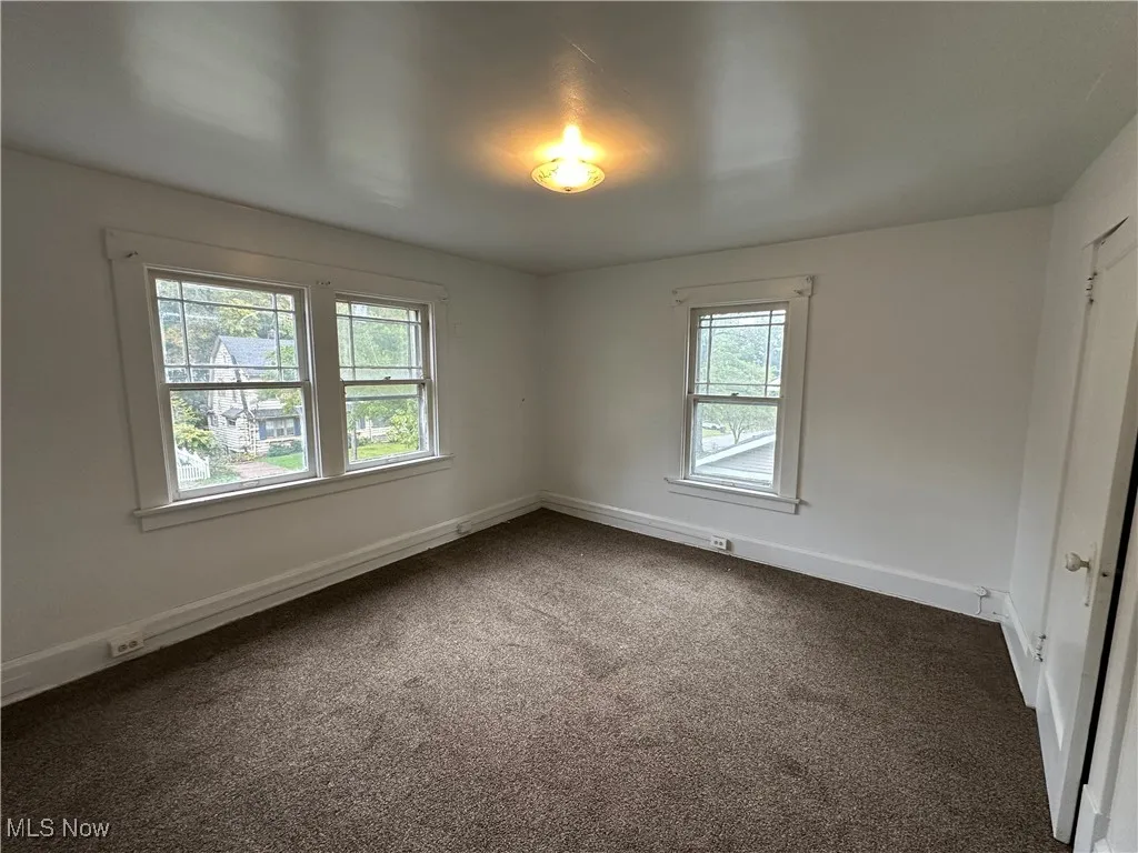 Empty room with dark carpet and baseboards