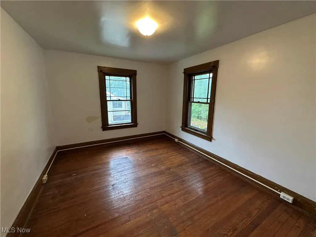 Empty room with baseboards and dark wood-style flooring