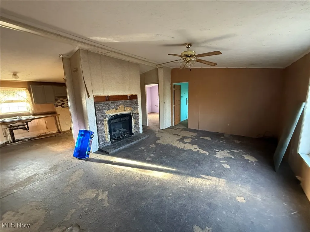 Unfurnished living room featuring a fireplace and ceiling fan