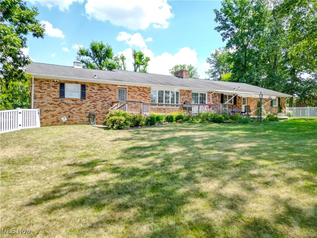 Back of property featuring a chimney, brick siding, and a deck