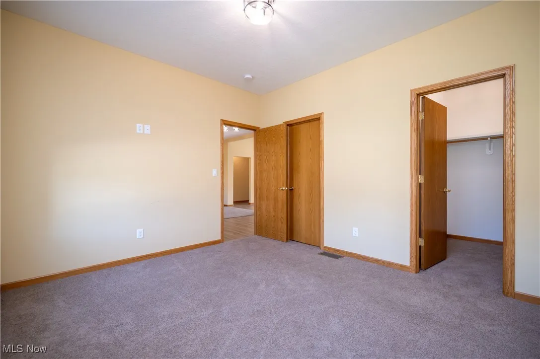 Unfurnished bedroom featuring carpet flooring and a walk in closet