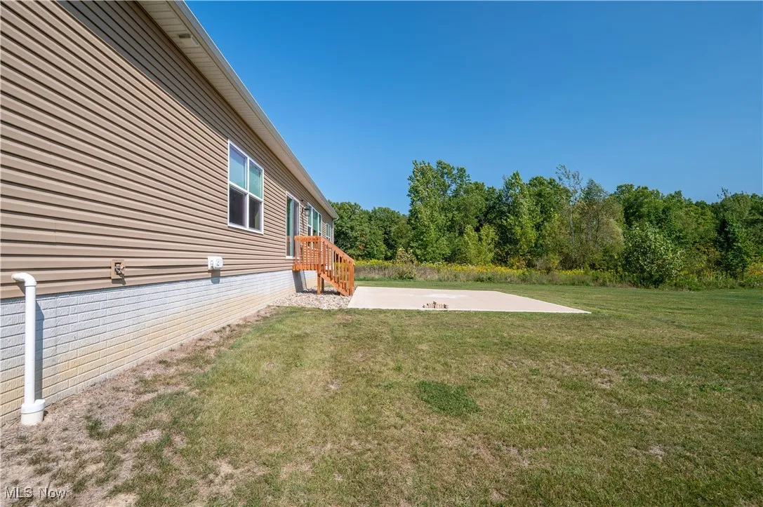 View of grassy yard featuring a patio