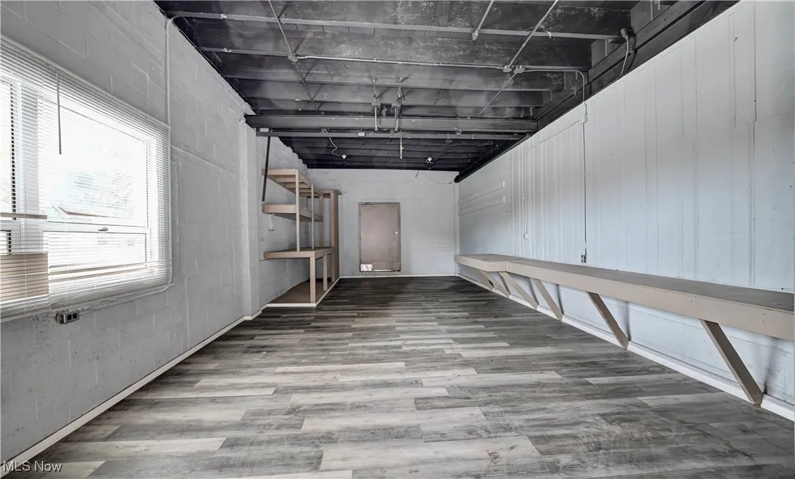 Basement with light wood-style flooring and concrete block wall