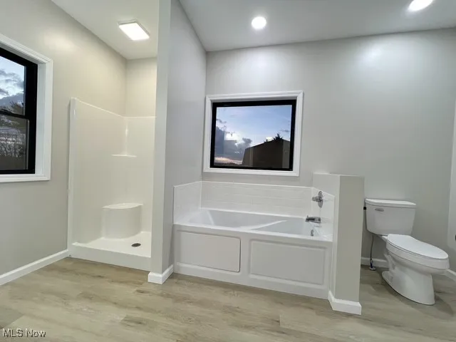 Full bathroom with a garden tub, a walk in shower, light wood-type flooring, and recessed lighting