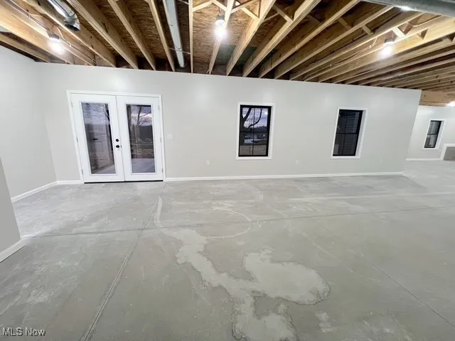 Unfinished below grade area with baseboards and french doors