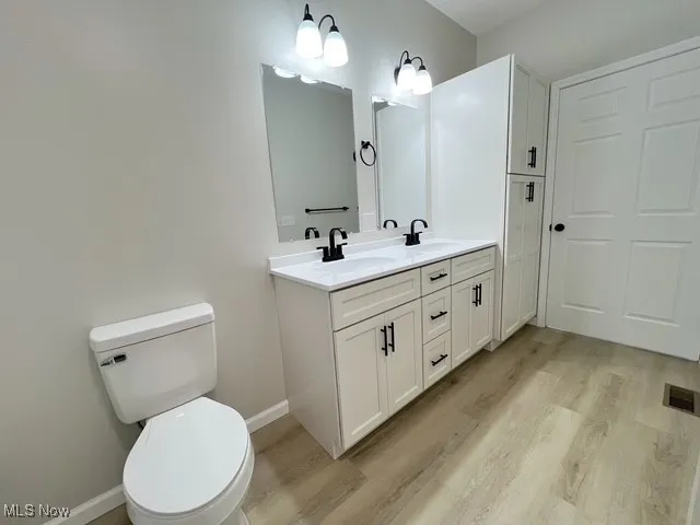 Full bathroom with double vanity and light wood-type flooring