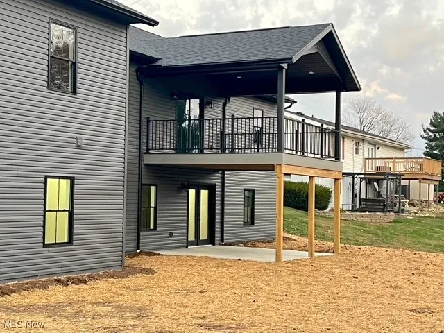 Back of property with a patio area, a shingled roof, a deck, and a yard