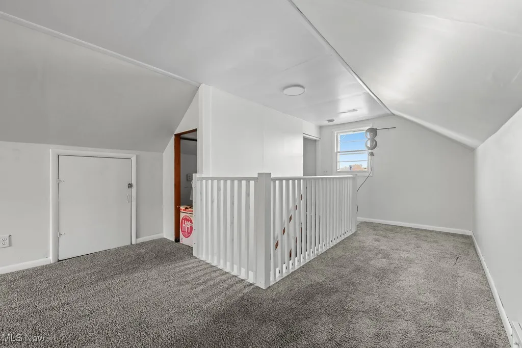 Additional living space with vaulted ceiling and carpet