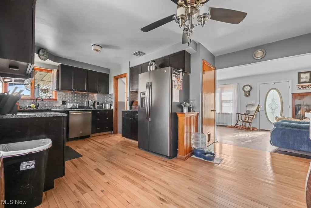 Kitchen with plenty of natural light, appliances with stainless steel finishes, decorative backsplash, and light wood finished floors