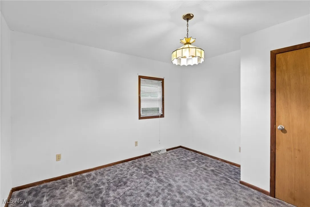 Unfurnished room featuring dark colored carpet and baseboards